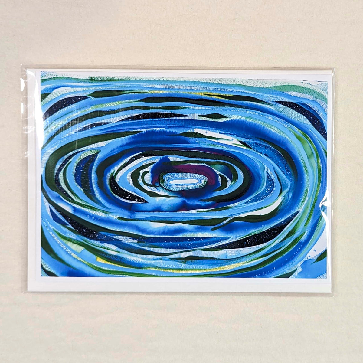 Notecard of artwork of Concentric puddle of blue and green circles on a neutral background