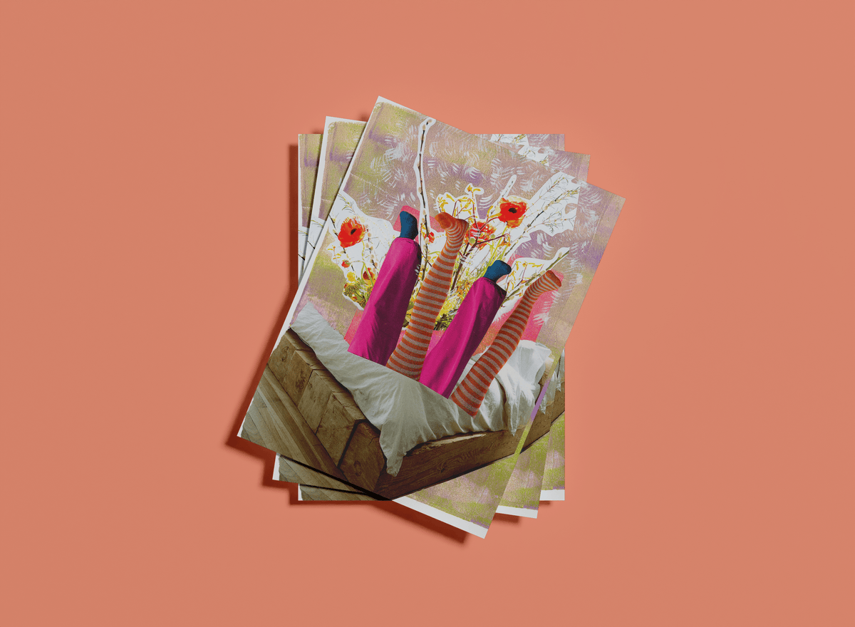 Stack of art prints on a coral pink background. Art print shows two sets of legs sticking up out of a bed with flowers and sticks showing behind the legs.